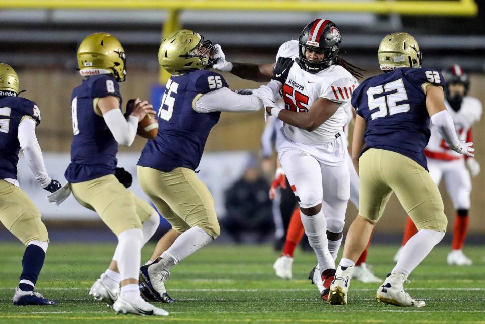 Aliquippa's Omar Banks (55) grabs the face mask of Bishop McDevitt's Riley Robell (55) while pressuring quarterback Stone Saunders (8) in the first quarter of the PIAA Class 4A championship football game, Dec. 9, 2021, at HersheyPark Stadium in Hershey. The Quips defeated the Crusaders 34-27. 