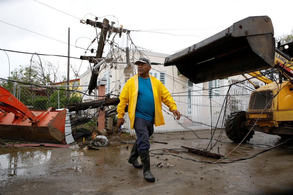 Workers use backhoe loaders to remove damaged electrical installations from a street in Salinas, Puerto Rico, Sept. 21, 2017. (Photo: Carlos Garcia Rawlins / Reuters)