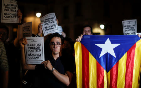 Protesters hold up signs reading " Freedom Political Prisoners, Sanchez Cuixart" outside the regional government headquarters after Spain's High Court jailed the leaders of two of the largest separatist organizations, the Catalan National Assembly's Jordi Sanchez and Omnium's Jordi Cuixart, in Barcelona, Spain, October 16, 2017. REUTERS/Gonzalo Fuentes