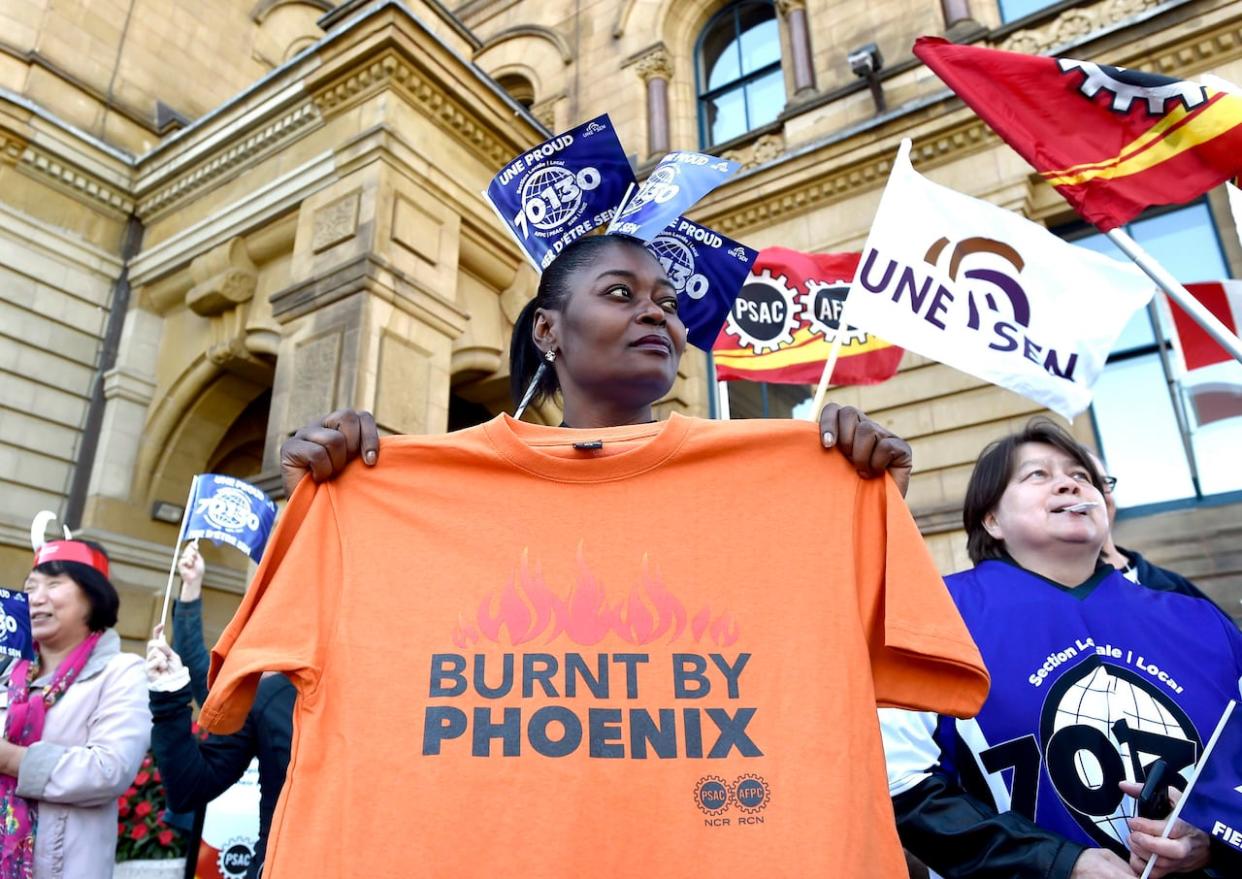 A member of Union Local 70130 holds a shirt during a protest against the Phoenix pay system outside the Office of the Prime Minister and Privy Council in Ottawa on Thursday, Oct. 12, 2017. (Justin Tang/The Canadian Press - image credit)