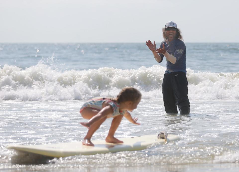 Atsushi "Hot Sushi" Yamada claps as a student surfs into shore Thursday during Hot Sushi's Happy Surf Camp Aloha on Tybee Island. Yamada was happy to be back in the water working with children just two days after being bitten by a shark near this very spot.