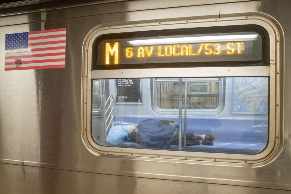 A man sleeps on an empty M train during to the coronavirus pandemic, Friday, April 10, 2020, in New York. The new coronavirus causes mild or moderate symptoms for most people, but for some, especially older adults and people with existing health problems, it can cause more severe illness or death. (AP Photo/Mary Altaffer)