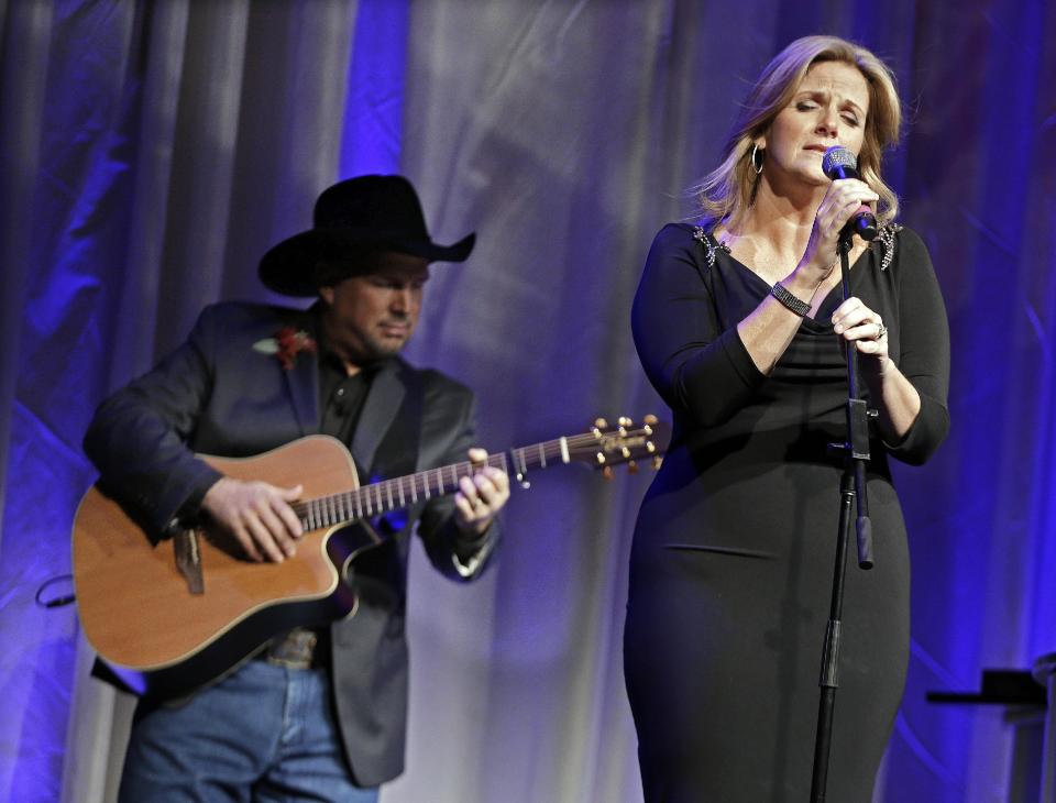 Trisha Yearwood is accompanied by her husband, Garth Brooks, as she sings "Wind Beneath My Wings," a song written by Larry Henley, as Henley is inducted into the Nashville Songwriters Hall of Fame on Sunday, Oct. 7, 2012, in Nashville, Tenn. (AP Photo/Mark Humphrey)