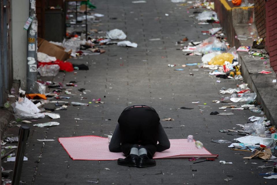 The clerk of a shop situated on the site where a stampede happened during Halloween festivities pays respects in the middle of the site (REUTERS)