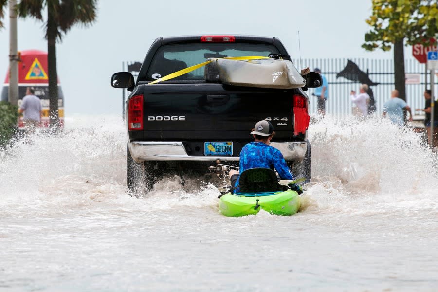 A truck pulls a man on a kayak on a low-lying road after flooding in the aftermath of Hurricane Ian, in Key West, Fla., Wednesday afternoon, Sept. 28, 2022. (AP Photo/Mary Martin)