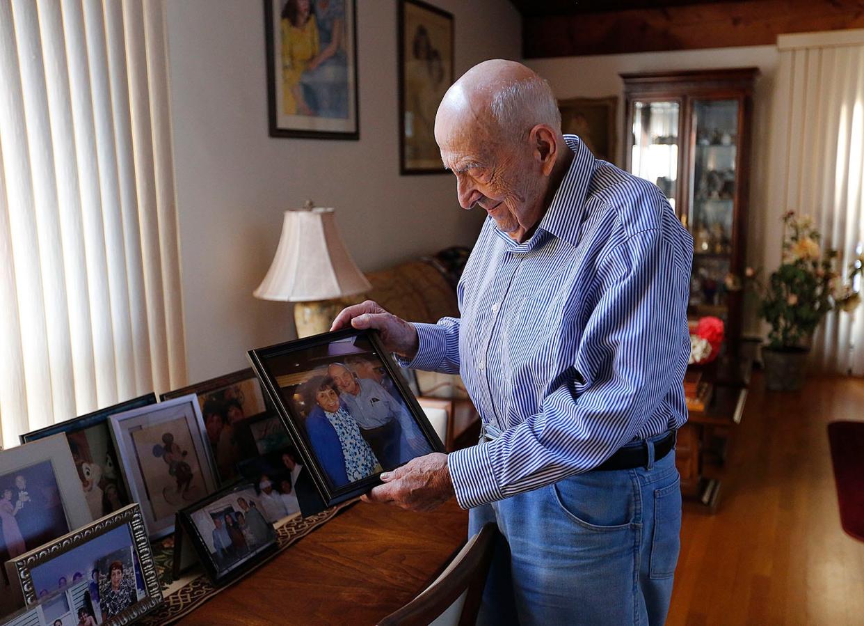 Carmine "Charlie" Mazzulli looks over family photos in the dining room of his Hingham home.