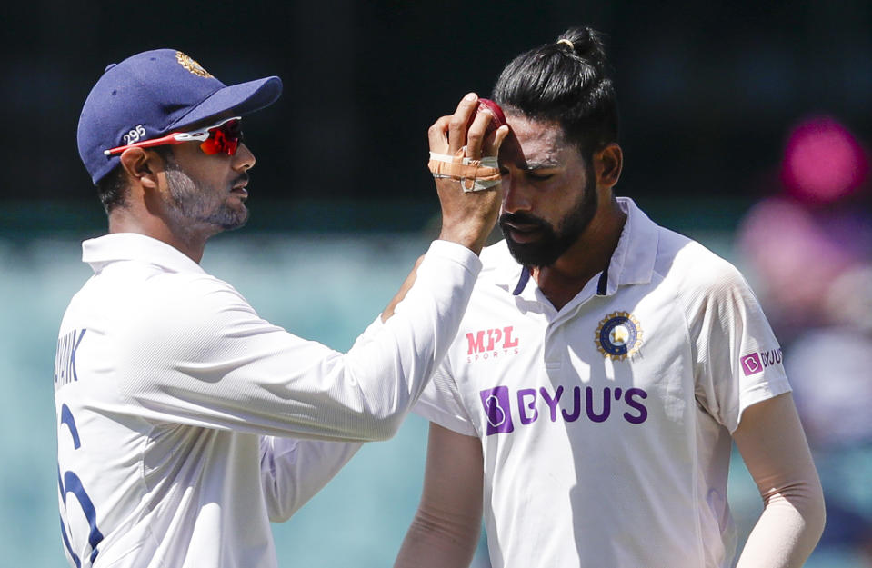 India's Mayank Agarwal, left, rubs the ball on the face of India's Mohammed Siraj during play on day four of the third cricket test between India and Australia at the Sydney Cricket Ground, Sydney, Australia, Sunday, Jan. 10, 2021. (AP Photo/Rick Rycroft)