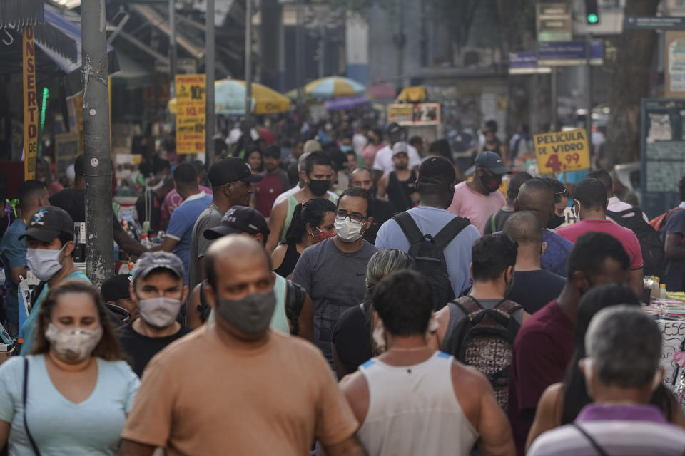 Transeúntes, la mayoría con mascarillas debido al coronavirus, recorren un mercado callejero en el centro de Río de Janeiro, Brasil, el jueves 25 de junio de 2020. (AP Foto/Leo Correa)