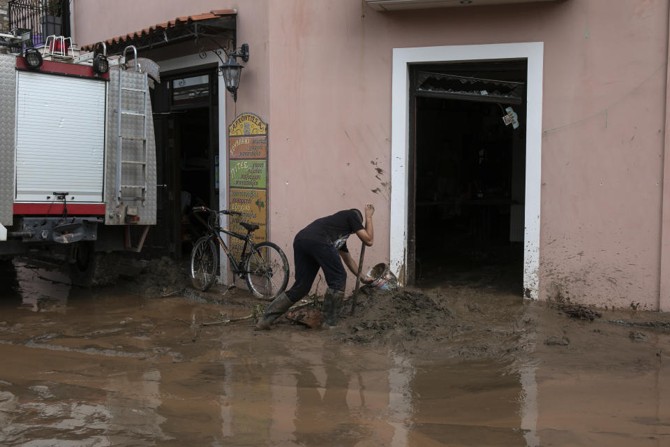 A man tries to move water and mud from his shop following a storm at the village of Politika, on Evia island, northeast of Athens, on Sunday, Aug. 9, 2020. Five people, including en elderly couple and an 8-month-old baby have been found dead, two more are missing and dozens have been trapped in their homes and cars as a storm hits the island of Evia in central Greece, authorities said Sunday. (AP Photo/Yorgos Karahalis)