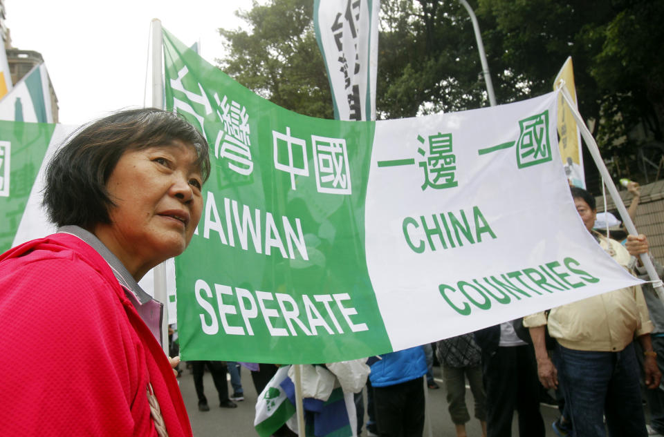 A protester stands beside a slogan reading: "Taiwan China separate countries" during a rally in Taipei, Taiwan, Saturday, Oct. 20, 2018. Thousands of pro-independence demonstrators gathered in Taiwan’s capital on Saturday to express their disapproval with China’s stance toward their island. (AP Photo/Chiang Ying-ying)