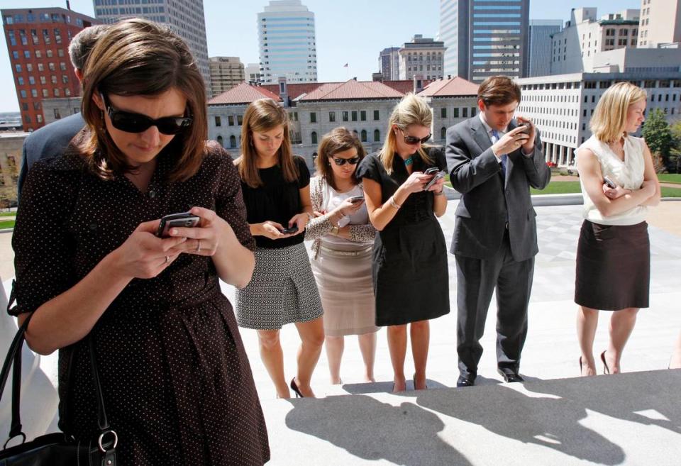 In this 2010 photo, staff members in the administration of Virginia Gov. Bob McDonnell, including Generra Peck (third from left), check their mobile devices during a press conference at the State Capitol in Richmond, Va., Wednesday, March 31, 2010. (AP Photo/Richmond Times-Dispatch, Bob Brown). BOB BROWN/ASSOCIATED PRESS