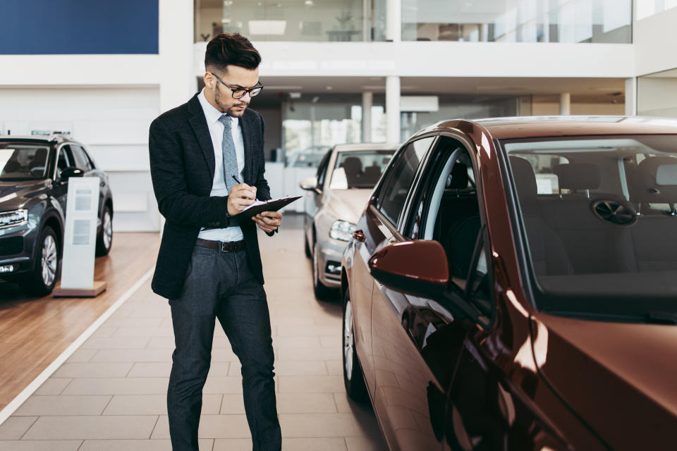 Car seller working in showroom and quality control checking of car details for the last time before buyer comes.