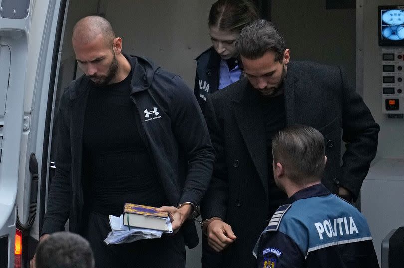 Andrew Tate holds a Quran as he is escorted out of a police van by his brother Tristan