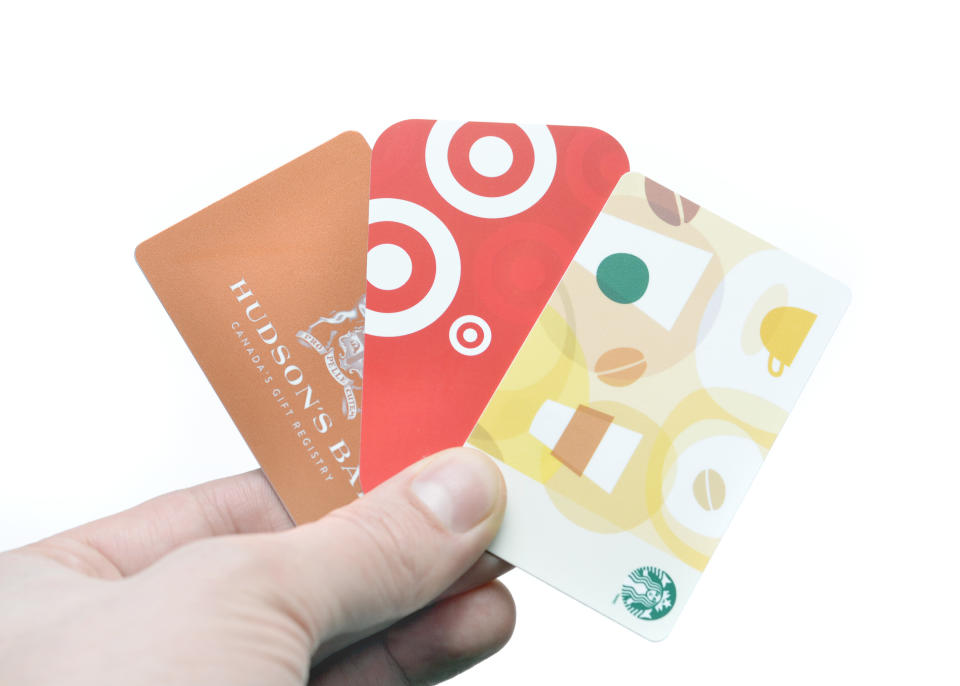 Vancouver, B.C., Canada -- December 12, 2014:Close up of a man holding a variety of gift cards against a white background.  Included businesses are Hudson's Bay, Target and Starbucks.