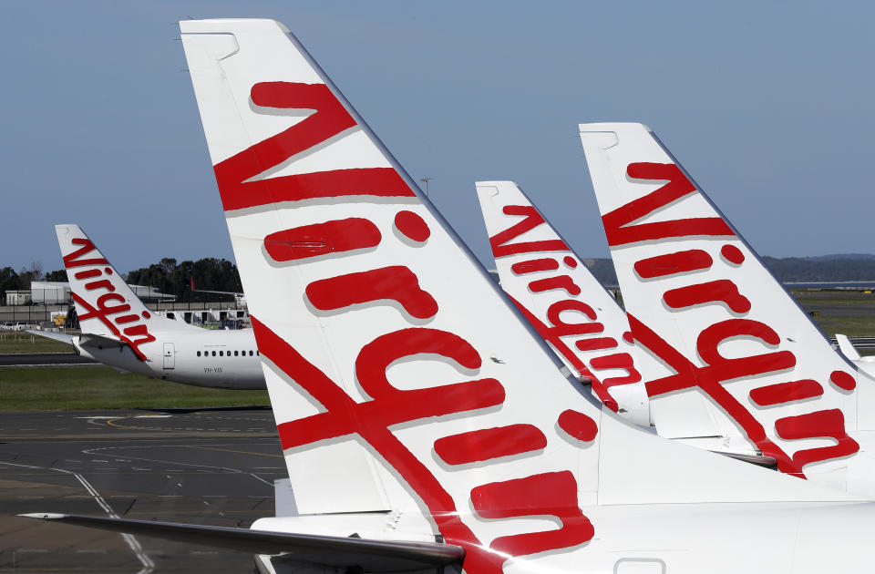 Virgin Australia planes are lined up at departure gates at Sydney Airport in Sydney, Wednesday, April 22, 2020. Virgin Australia is seeking bankruptcy protection, entering voluntary administration after a debt crisis worsened by the coronavirus shutdown pushed it into insolvency. (AP Photo/Rick Rycroft)
