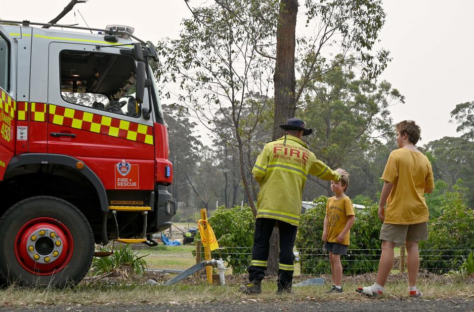 A firefighter talks to residents in Old Bar, NSW.