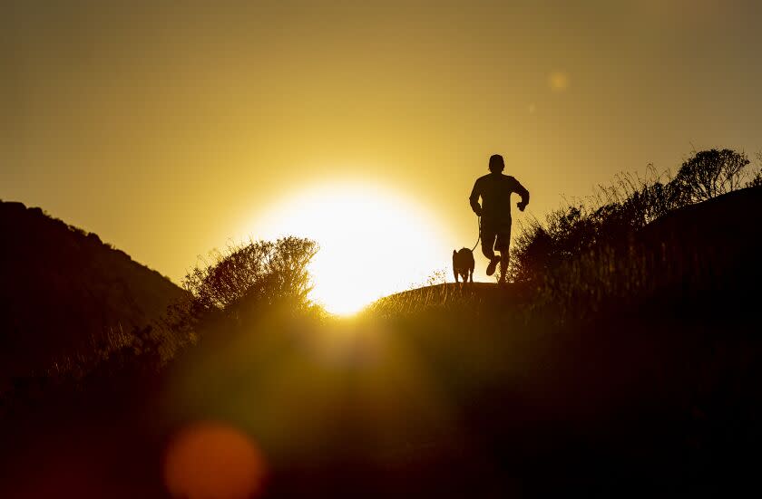 RIVERSIDE, CA - SEPTEMBER 27, 2022: With temperatures reaching triple-digits on Tuesday, a resident takes advantage of the 90 degree temps at dusk to get in a jog with his dog at Challen Park on September 27, 2022 in Riverside, California. The September heat wave brought triple-digit temps to the Inland Empire as the National Weather Service issued heat warnings for Southern California for the week.(Gina Ferazzi / Los Angeles Times)