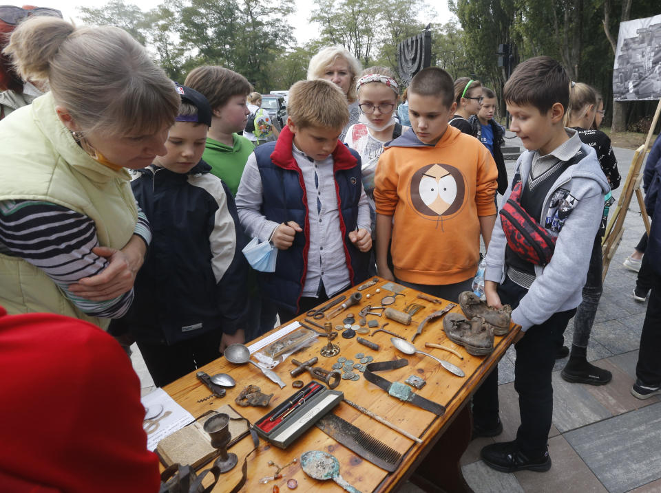 Children look at personal items found on the site of the Babi Yar tragedy at a menorah monument close to a Babi Yar ravine where tens of thousands of Jews were killed during WWII, in Kyiv, Ukraine, Tuesday, Sept. 29, 2020. Ukraine marked the 79th anniversary of the 1941 Babi Yar massacre. (AP Photo/Efrem Lukatsky)