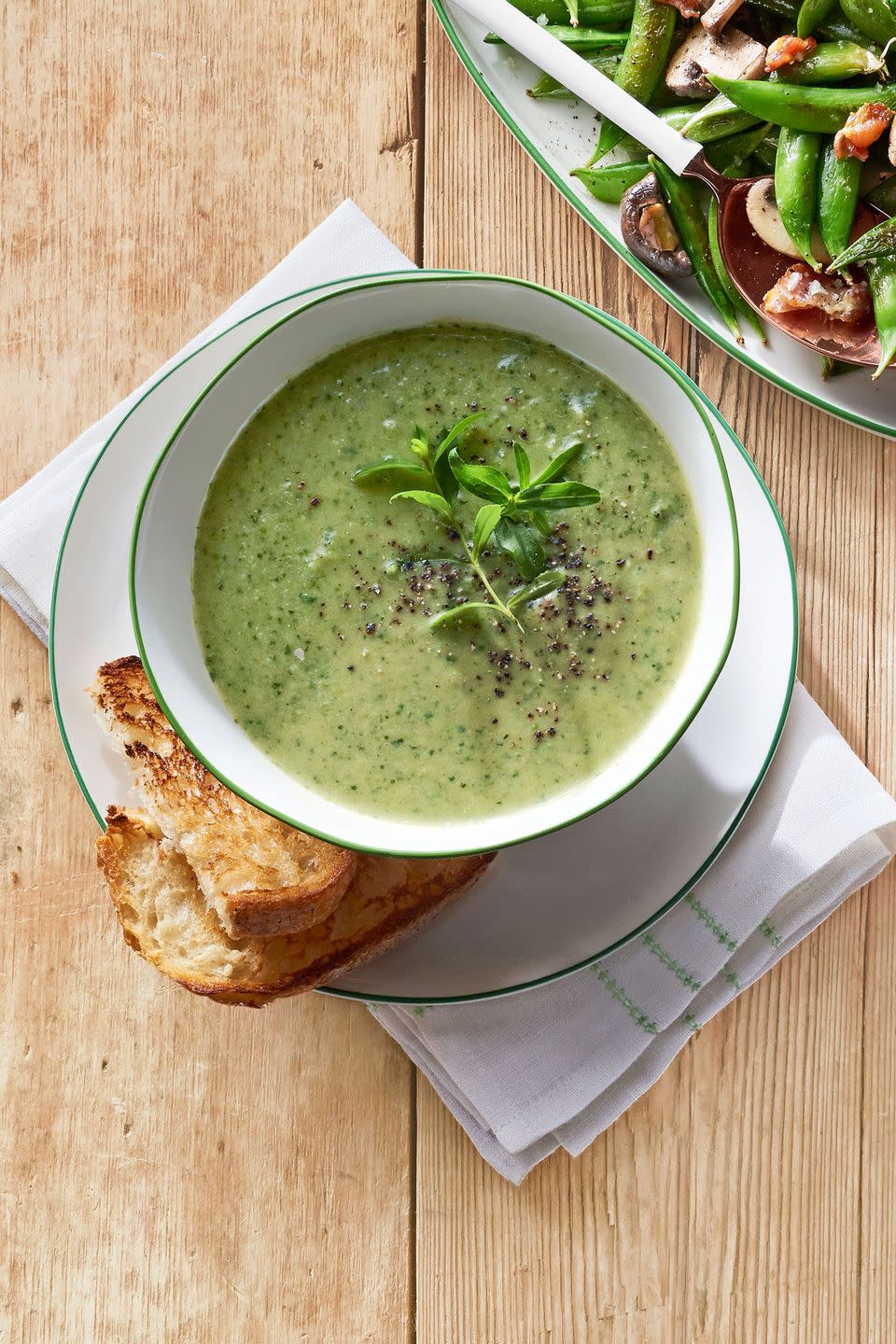 snap pea and lettuce soup in a white bowl with green trim and served with toasted bread