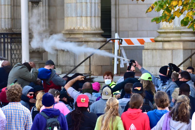 Law enforcement officers spray protesters shortly after a moment of silence during a Get Out The Vote march in Graham