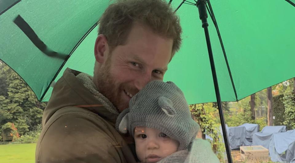 <p>Harry cuddles a baby Archie underneath a green umbrella.</p>