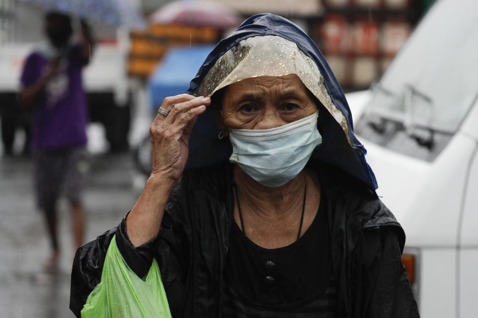 A woman wearing a face mask to prevent the spread of the coronavirus walks as rains from a typhoon locally known as Goni starts in Manila, Philippines on Sunday Nov. 1, 2020. The super typhoon slammed into the eastern Philippines with ferocious winds early Sunday and about a million people have been evacuated in its projected path, including in the capital where the main international airport was ordered closed. (AP Photo/Aaron Favila)