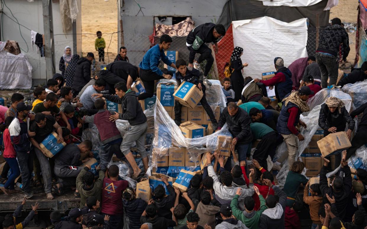 Palestinians loot a humanitarian aid truck as it crossed into the Gaza Strip in Rafah