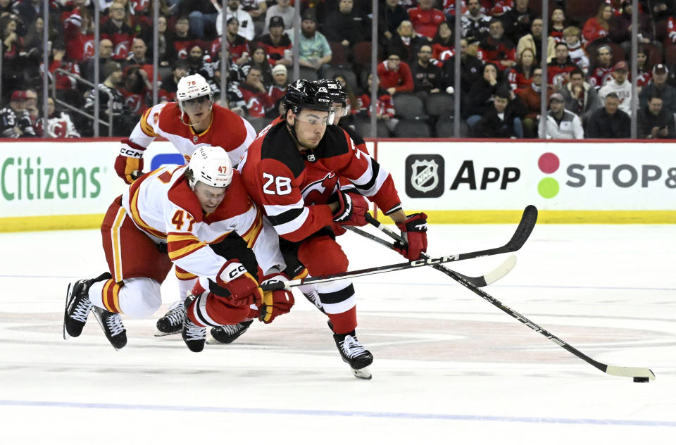 New Jersey Devils right wing Timo Meier (28) skates with the puck as he is checked by Calgary Flames center Connor Zary (47) during the second period of an NHL hockey game Thursday, Feb. 8, 2024, in Newark, N.J.(AP Photo/Bill Kostroun)