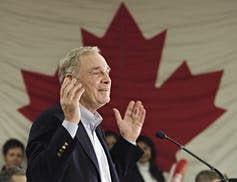 Paul Martin gestures while making a speech with the Canadian flag in the background.