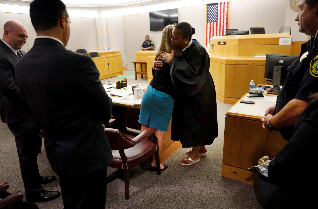 Amber Guyger leaps from her chair and gives Tammy Kemp a hug after she had given her a Bible, Guyger's 10-year prison sentence for murder at the Frank Crowley Courts Building in Dallas, Texas, U.S. October 2, 2019.  Tom Fox/Pool via REUTERS.  MANDATORY CREDIT