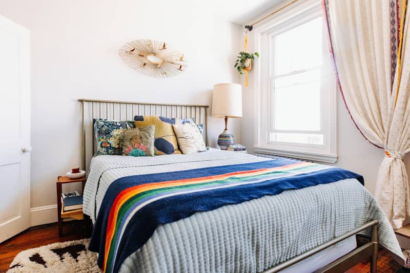Bed with colorful pillows below a goose theme mirror.