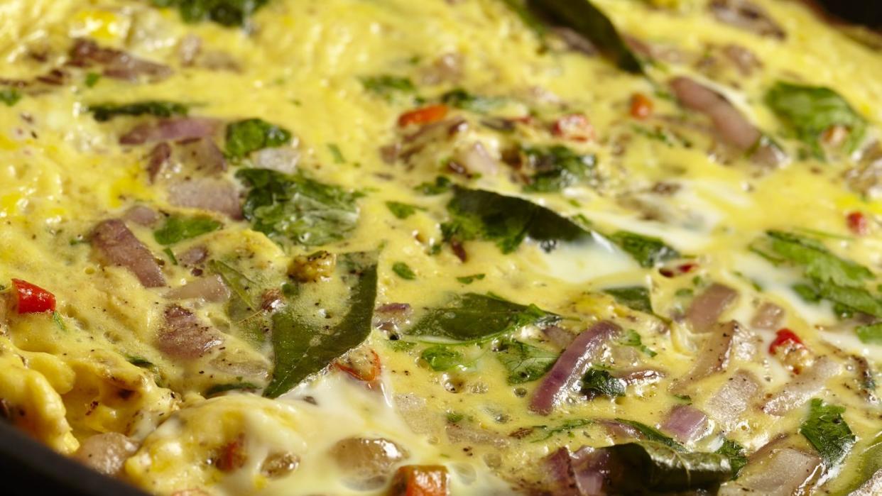 a masala omlette being fried in a pan close up