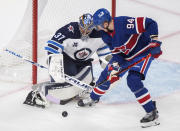 Montreal Canadiens' Corey Perry moves in against Winnipeg Jets goaltender Connor Hellebuyck during first-period NHL hockey game action in Montreal, Saturday, April 10, 2021. (Graham Hughes/The Canadian Press via AP)