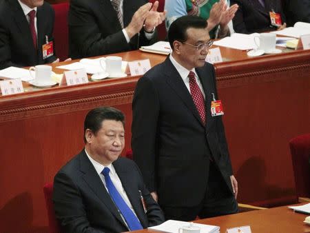 Chinese President Xi Jinping sits as Premier Li Keqiang stands next to him during the opening of the annual full session of the National People's Congress, the country's parliament, at Great Hall of the People, in Beijing, March 5, 2015. REUTERS/Barry Huang