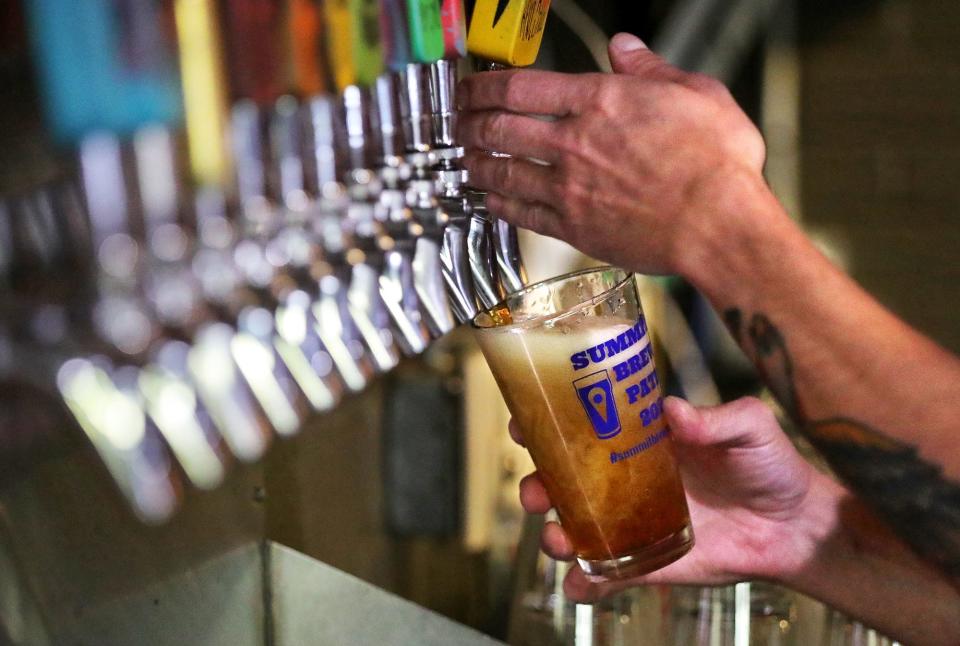 A worker pours a beer for a customer at Madcap Brew Co., Wednesday, July 21, 2021, in Kent, Ohio.