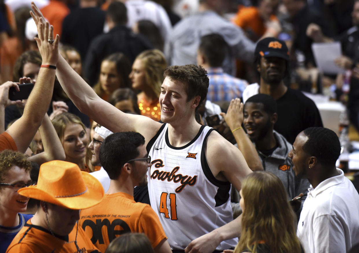 Oklahoma State forward Mitchell Solomon celebrates with fans that stormed the court following an NCAA college basketball game against Kansas in Stillwater, Okla., Saturday, March 3, 2018. (AP Photo/Brody Schmidt)