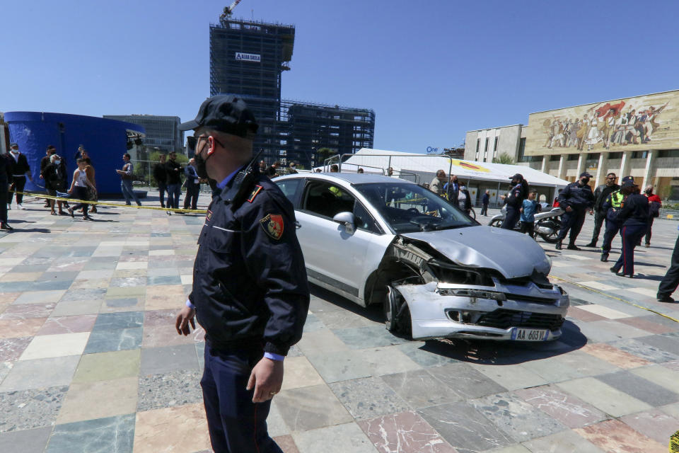 A police officer stands near to a damaged car on central Skanderbeg square, after an incident, in Tirana, Sunday, April 25, 2021. A man drove his car into the Albanian capital Tirana’s main square where vehicles are not allowed, the local media and police reported on Sunday. The driver broke the barriers to enter the Skanderbeg Square. A young man managed to stop the driver entering from the window. Then people dragged him out of the car. No one was injured. The car stopped near two big tents where people get vaccines and a smaller tent raised from the Syri Televizion private channel to cover the voting. (AP Photo/Hektor Pustina)