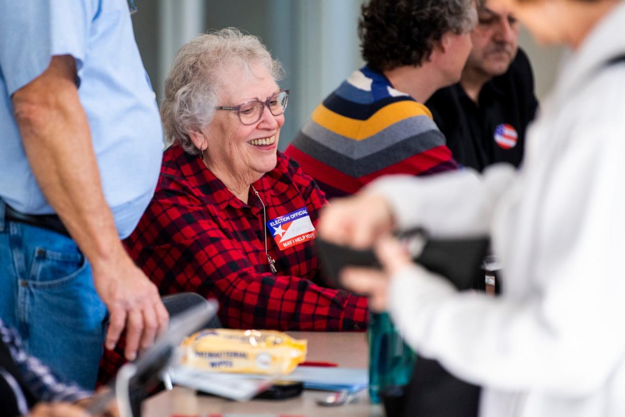 Karen Whiteside checks people in to vote at Bloomington High School South in November 2022.