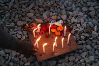 A student lights candles near the spot where a 23-year-old rape victim was set on fire by a gang of men, which included her alleged rapists, in Unnao