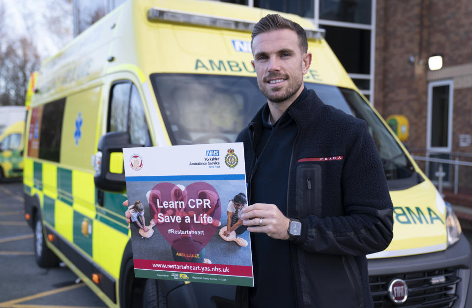 Jordan Henderson holds an NHS 'Learn CPR save a life' sign during a visit to the Yorkshire Ambulance Service in 2022.