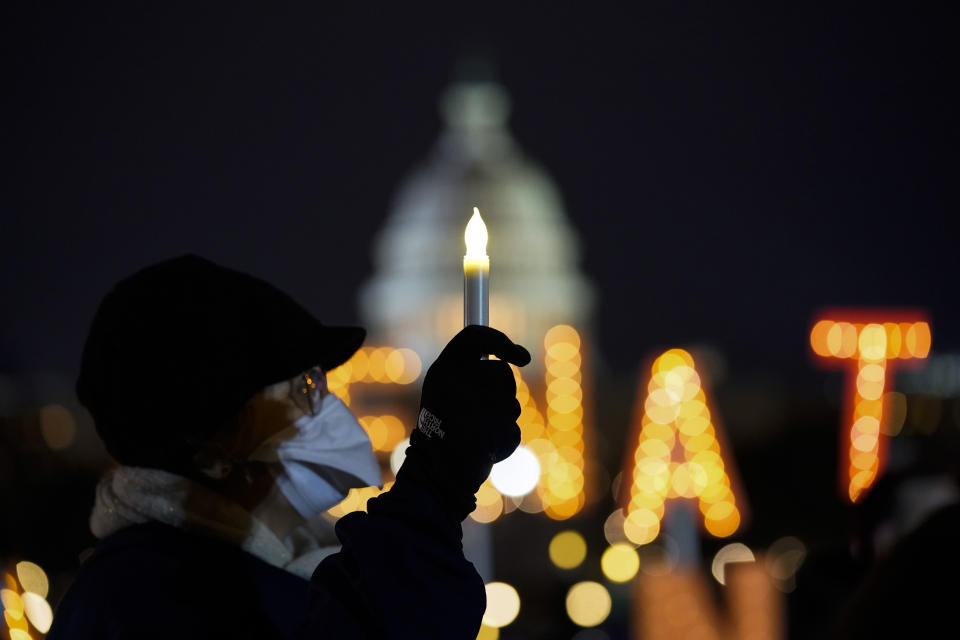 With the U.S. Capitol building in the background, a person holds a candle during a vigil Thursday, Jan. 6, 2022, in Washington, on the one year anniversary of the attack on the U.S. Capitol. (AP Photo/Evan Vucci)