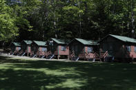 In this Thursday, June 4, 2020 photo, a row of cabins will soon be occupied by campers at the Camp Winnebago summer camp in Fayette, Maine. The boys camp is going ahead with plans to open with a reduction in the number of campers and other changes to comply with guidelines for helping prevent the spread of the coronavirus. Many of the nation's 15,000-plus summer camps opting to close because of health concerns surrounding the pandemic, or because of delays in receiving rules or guidelines from licensing officials. (AP Photo/Robert F. Bukaty)