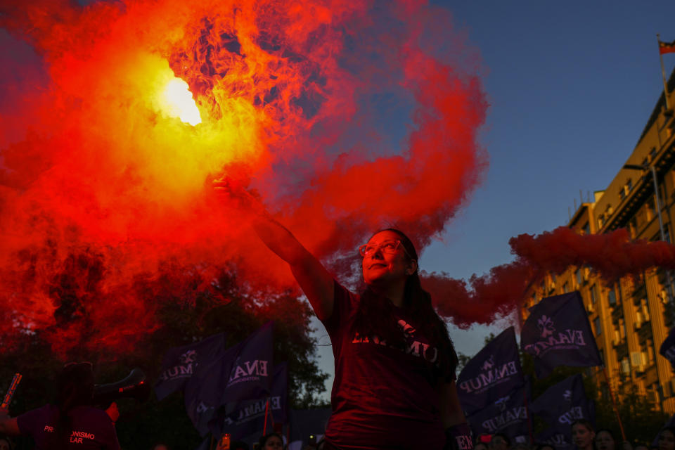 Una mujer con una bengala en el palacio presidencial de La Moneda durante la marcha por el Día Internacional de la Mujer, en Santiago, Chile, el viernes 8 de marzo de 2024. (AP Foto/Esteban Félix)