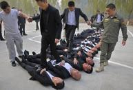 Trainees walk over the bodies of their fellow trainees during the Tianjiao Special Guard/Security Consultant Ltd. bodyguard training camp in Beijing, November 2, 2013. Trainees include former soldiers, college graduates and retired athletes. About 65 people took part in the intensive training camp teaching Israeli martial arts, driving, shooting and business etiquette. Picture taken November 2, 2013. REUTERS/Stringer (CHINA - Tags: SOCIETY EDUCATION TPX IMAGES OF THE DAY) CHINA OUT. NO COMMERCIAL OR EDITORIAL SALES IN CHINA