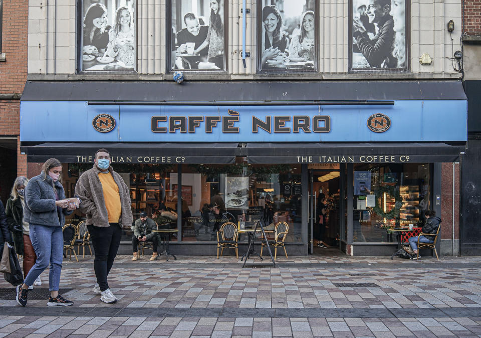 BELFAST, ANTRIM, UNITED KINGDOM - 2020/12/22: A couple wearing face masks as a precaution against the spread of covid-19 walking past the Caffe Nero Coffee Shop. (Photo by Michael McNerney/SOPA Images/LightRocket via Getty Images)