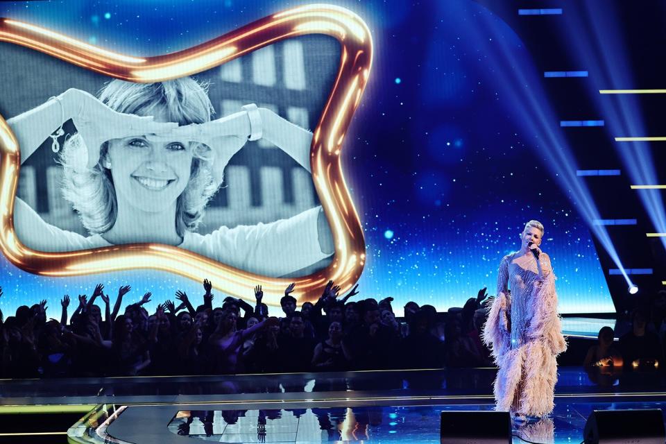 An image of the late Olivia Newton-John is displayed on a screen while P!nk performs onstage during the 2022 American Music Awards