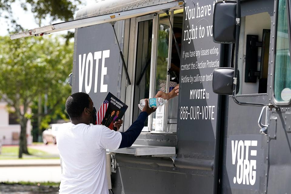 A voter gets a free bottle of water and a taco from a food truck sponsored by Vote.org outside of a polling place at the North Dade Regional Library during the general election, Tuesday, Nov. 3, 2020, in Miami Gardens, Fla.