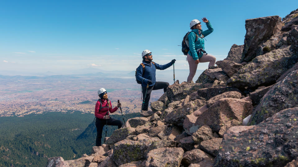 Three hikers climbing a rocky slope