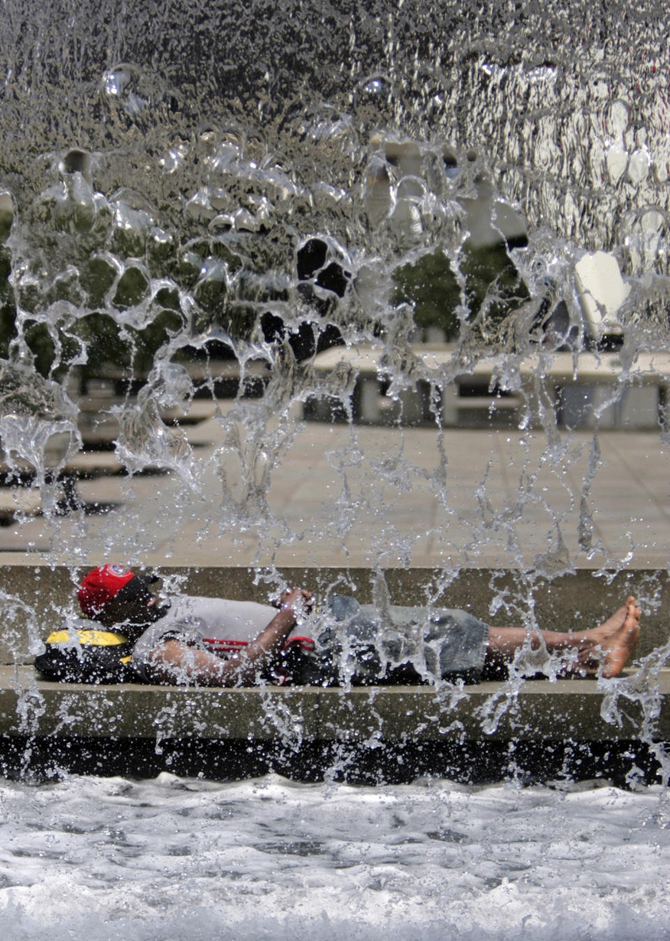 FILE - A man sleeps on the edge of a waterfall in the courtyard of Philadelphia's City Hall on Tuesday, June 19, 2007, as hot, humid weather was expected for the region. George Widman is shown in this April, 2005 self-portrait. Widman, a longtime photographer for the Associated Press and others as well as a Pulitzer Prize finalist, died at his Trappe, Pa., home Friday, March 8, 2024. He was 79. (AP Photo/George Widman, File)