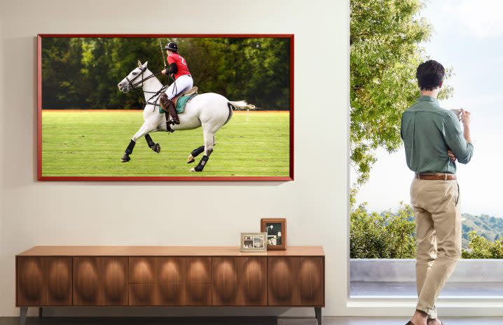 A Samsung The Frame TV displaying a person riding a horse playing polo.